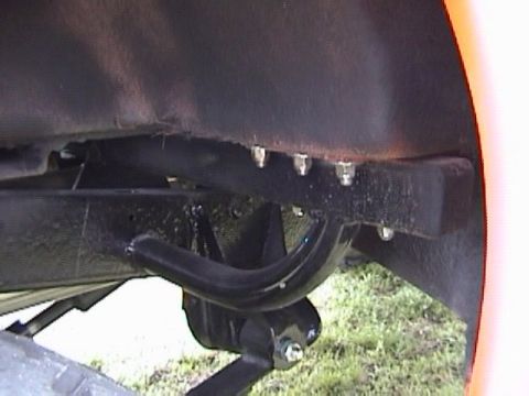 1995 Ford Bronco - Undercarriage view showing frame and suspension parts, with grass in the background.