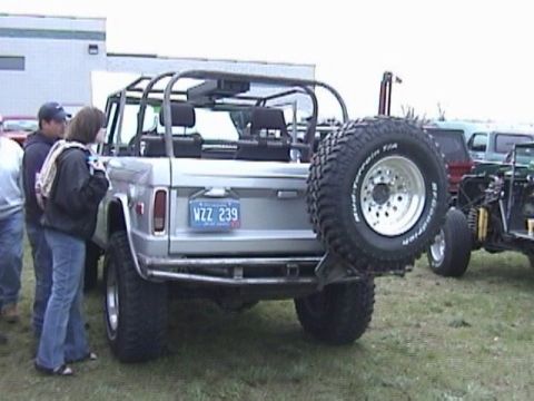 1995 Ford Bronco - This classic Ford Bronco features a roll cage and a rear-mounted spare tire, with other vehicles visible in the background.