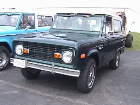 1995 Ford Bronco - This SUV, likely a 1975 Ford Bronco, is parked next to a blue vehicle. The registry claims it is a 1995 model.