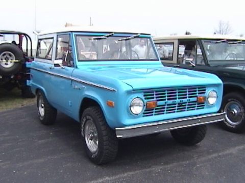 1995 Ford Bronco - A light blue first generation Ford Bronco is parked next to another Bronco.