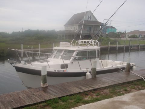 1995 Ford Bronco - A white cabin cruiser boat is docked next to a wooden pier on a cloudy day.