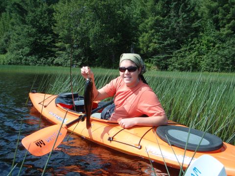 1995 Ford Bronco - A woman enjoys a day of fishing from her kayak on a calm body of water.