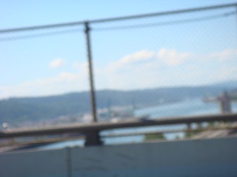 1992 Ford Bronco - A blurry scene with a fence and a body of water with hills in the distance.