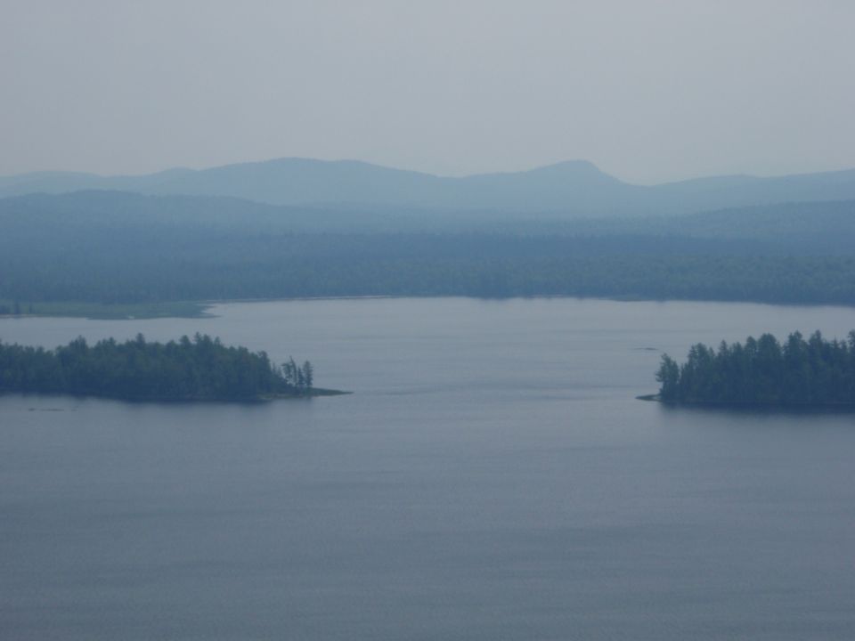 Lake and forested mountains under a hazy sky