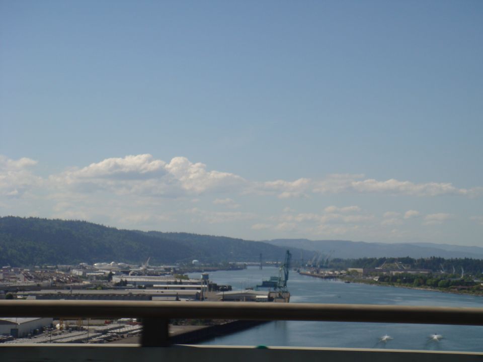 Waterfront industrial area with cranes and buildings along a river under a blue sky