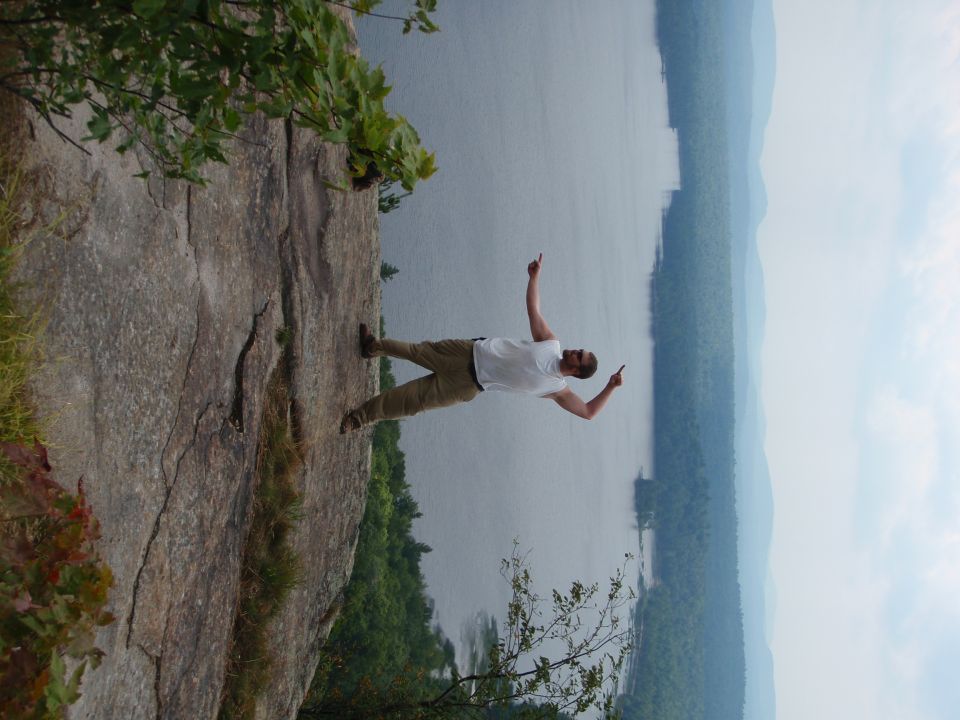 Man on cliff pointing at lake