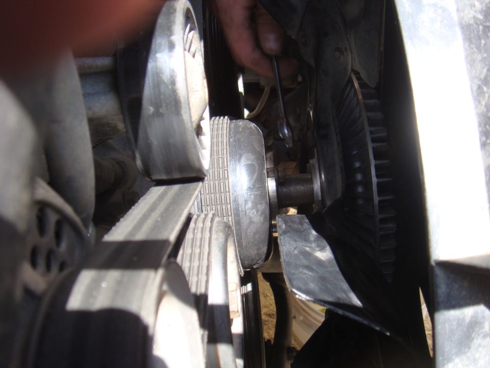 Close-up of engine belt and fan assembly with a wrench being used