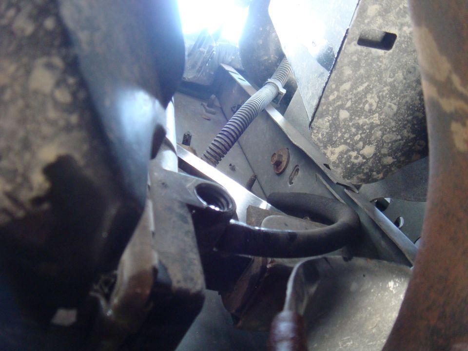 Undercarriage view of vehicle with hoses and metal components visible