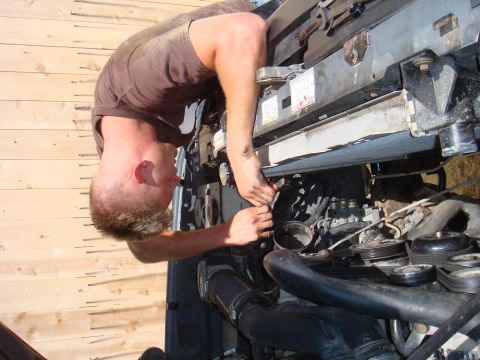 1992 Ford Bronco - Mechanic performing maintenance on a vehicle's engine compartment.