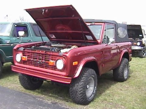 1995 Ford Bronco - A red 1978 Ford Bronco is displayed with its hood open, alongside other vehicles.