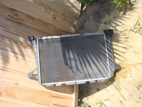 1992 Ford Bronco - A vehicle radiator is shown outdoors, placed on a wooden surface with shadows cast upon it.