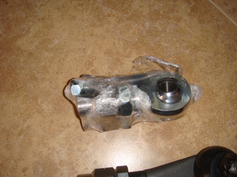 Metal automotive part wrapped in plastic, with bolts and a spherical joint visible
