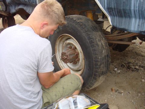 1992 Ford Bronco - Man works on the rear axle and wheel assembly of a vehicle.