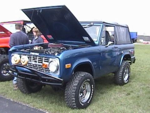 1995 Ford Bronco - This blue Ford Bronco, likely from the mid-1970s, is displayed with its hood open, revealing the engine compartment.
