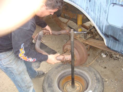1992 Ford Bronco - Mechanic works on the rear axle of a 1992 Ford Bronco, focusing on the exhaust system and suspension components.
