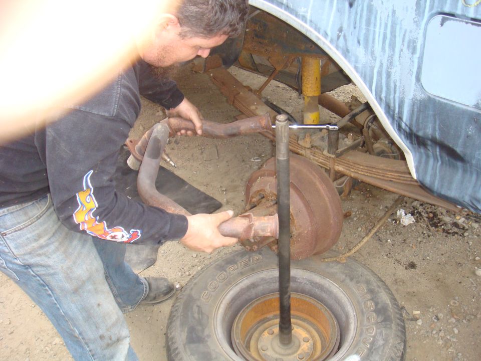 1992 Ford Bronco rear axle assembly with leaf springs and shock absorber, man removing exhaust pipe
