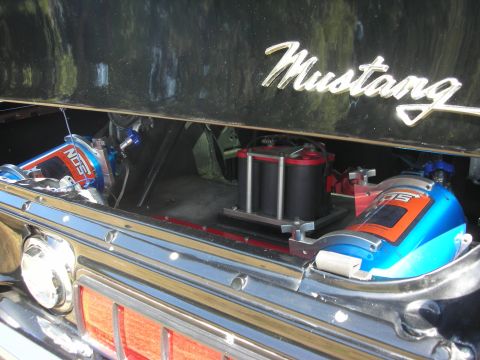 1992 Ford Crown Victoria - A car trunk is open, revealing NOS bottles and a 'Mustang' emblem on the black paint.