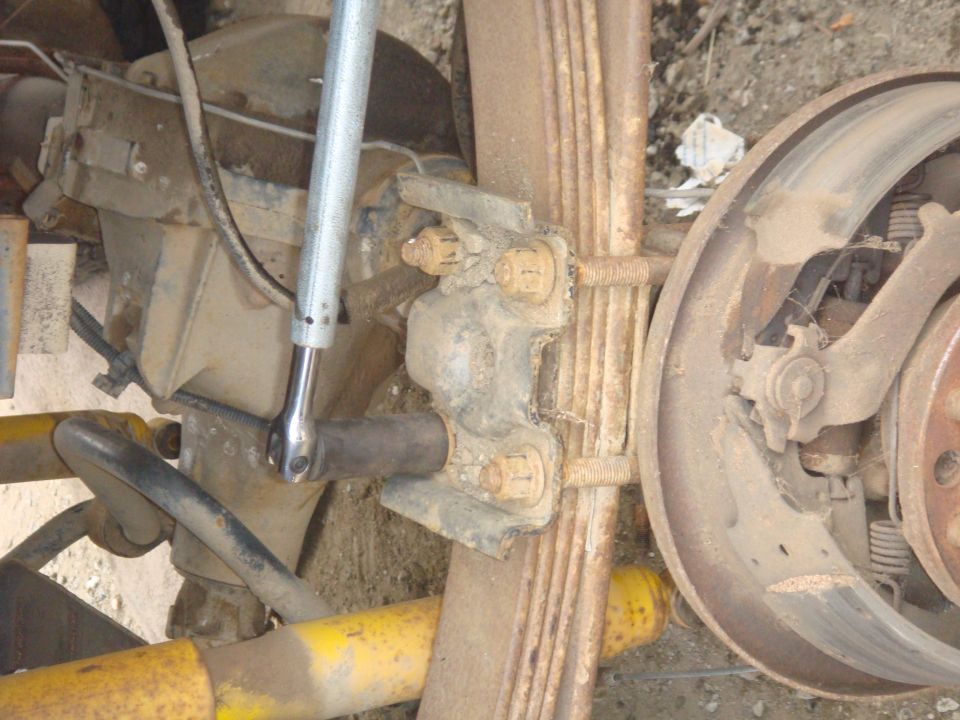 Rear axle assembly with leaf springs and brake drum, wrench on U-bolt