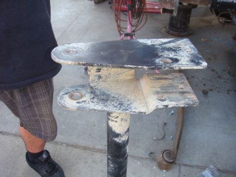 1992 Ford Bronco - A close-up of a dirty metal bracket assembly, likely a vehicle part, is shown against a concrete floor.
