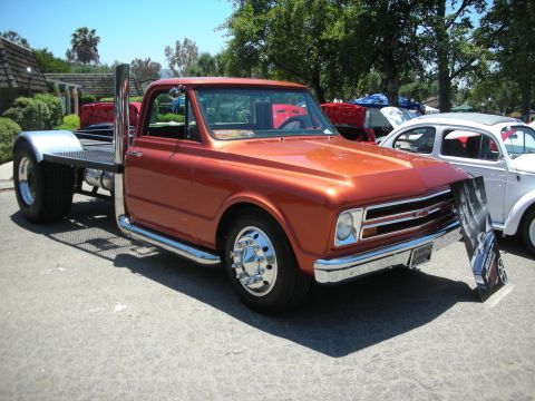 1992 Ford Crown Victoria - Customized orange flatbed truck with prominent exhaust stacks and chrome wheels, seen at a car show.