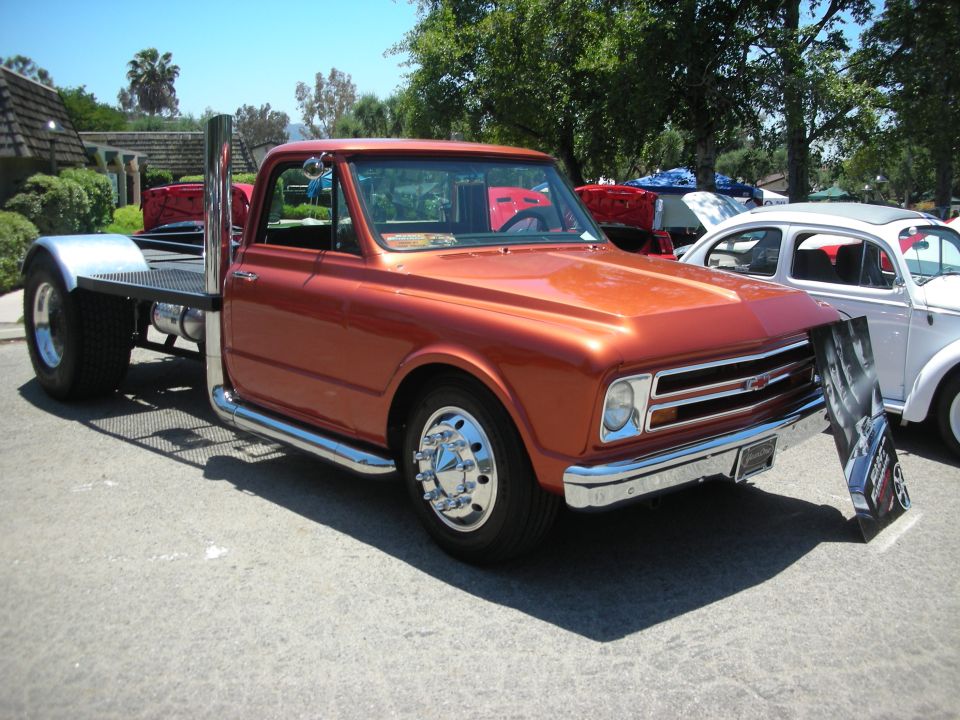 Orange flatbed truck with large exhaust pipes and dually rear wheels