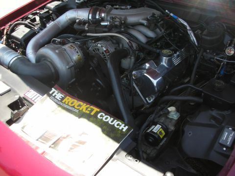 1992 Ford Crown Victoria - Close-up of a modified engine bay a supercharger and a magazine on the fender.