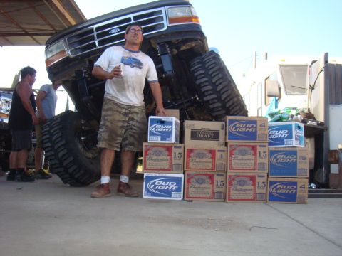 1992 Ford Bronco - A man stands with a beer next to a lifted 1992 Ford Bronco, surrounded by stacks of Bud Light and Budweiser cases.