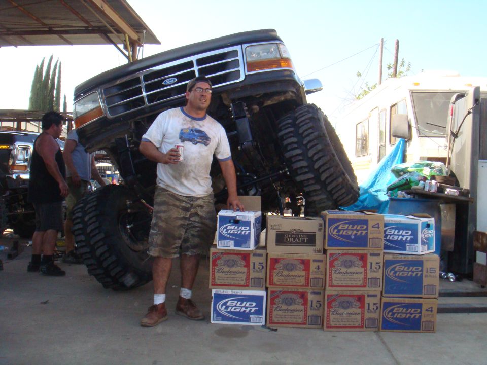 1992 Ford Bronco lifted high on large tires, man holding beer, stacks of Bud Light and Budweiser boxes