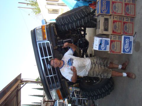 1992 Ford Bronco - A man points at a 1992 Ford Bronco with modified suspension, surrounded by cases of beer.