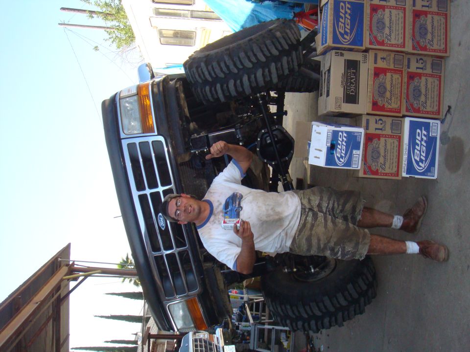 1992 Ford Bronco with lifted suspension, pointing man, and beer cases