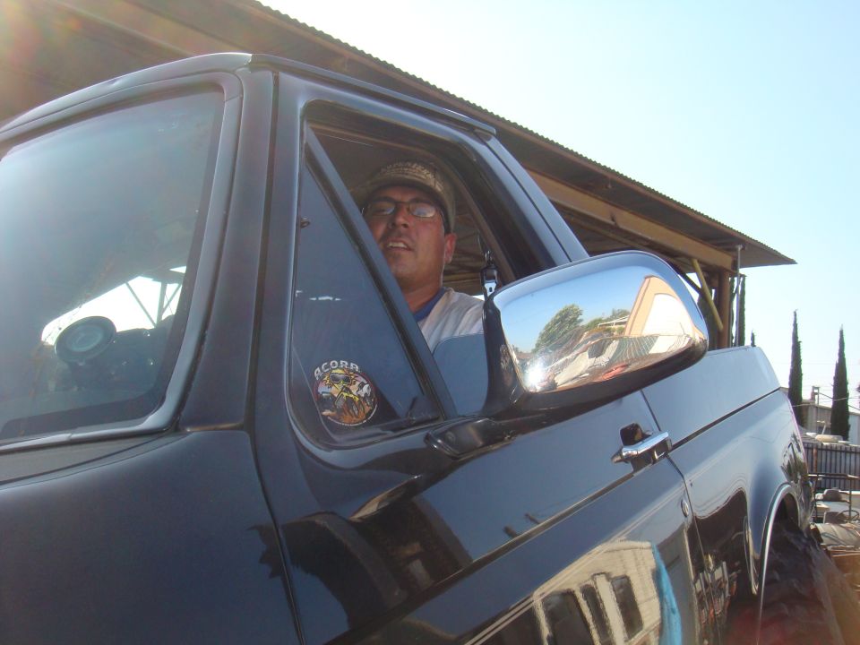 Side view of black SUV with a man inside and an "ACORN" sticker on the door