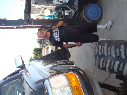 1992 Ford Bronco - A man stands next to a vehicle with oversized tires, with another vehicle visible in the background.