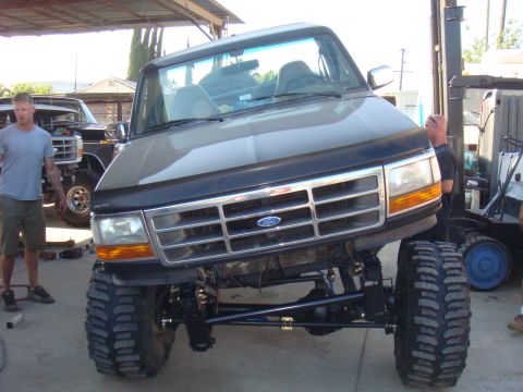 1992 Ford Bronco - Front view of a 1992 Ford Bronco with a lifted suspension and oversized tires, undergoing modifications.