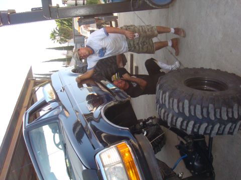 1992 Ford Bronco - Two men are working on a black Ford F-Series truck, which has a large spare tire mounted on its rear.