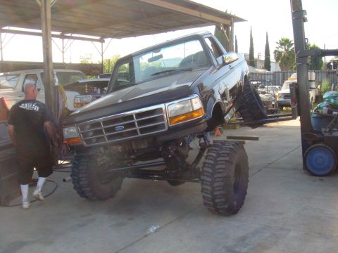 1992 Ford Bronco - Ford Bronco is being lifted by a forklift in an outdoor workshop area.