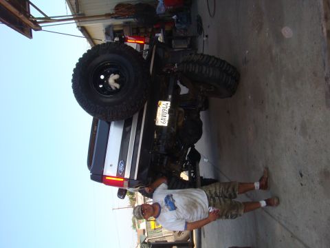 1992 Ford Bronco - A man stands next to a lifted 1992 Ford Bronco with oversized tires and a spare tire on the back.