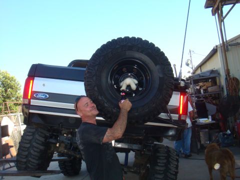1992 Ford Bronco - Man poses with a lifted 1992 Ford Bronco, holding a beer near the rear-mounted spare tire.