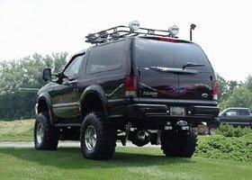 1995 Ford Bronco - This black Ford Excursion is equipped with a roof rack and off-road tires, seen from the rear three-quarter angle.