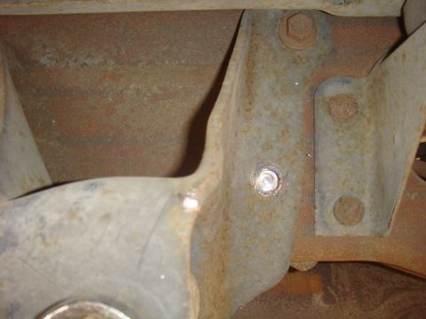1992 Ford Bronco - Close-up view of rusted metal bracket and bolts, possibly from a vehicle's undercarriage.