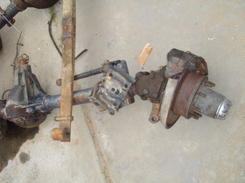 1992 Ford Bronco - Front axle assembly with leaf spring and chrome hub cap, likely from an older truck or SUV.