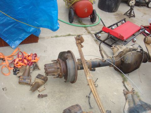1992 Ford Bronco - A disassembled rear axle assembly with leaf springs and brake drum lies on a concrete surface.