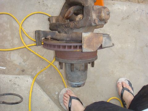 1992 Ford Bronco - A vehicle axle assembly with a brake rotor and hub is shown on a concrete surface with a yellow cord.
