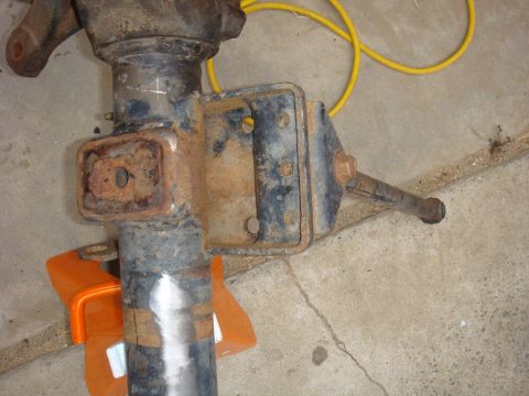 1992 Ford Bronco - Close-up of a rusty vehicle axle part supported by an orange jack stand.