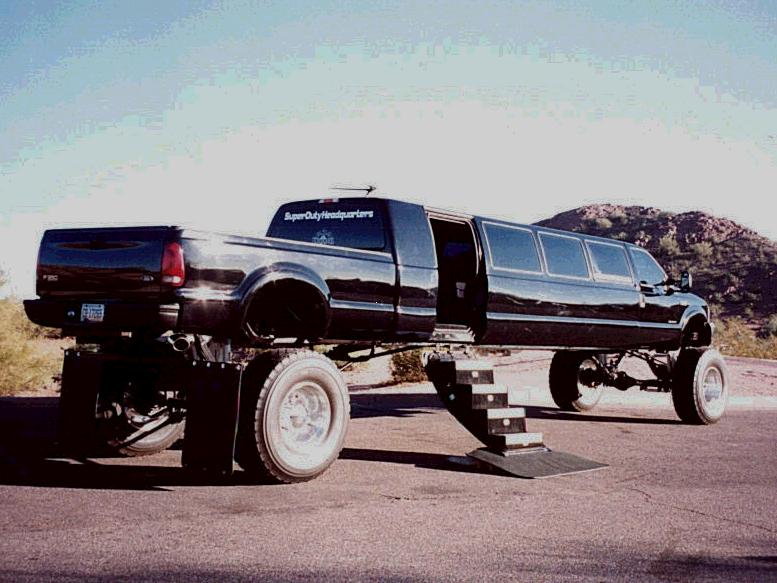 Lifted black Ford stretch limo pickup with white wheels and fold-out steps, rear view