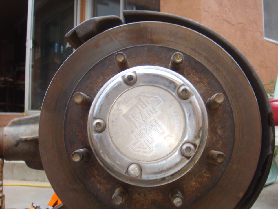 Wheel hub with a metal cap showing a logo, part of a brake rotor
