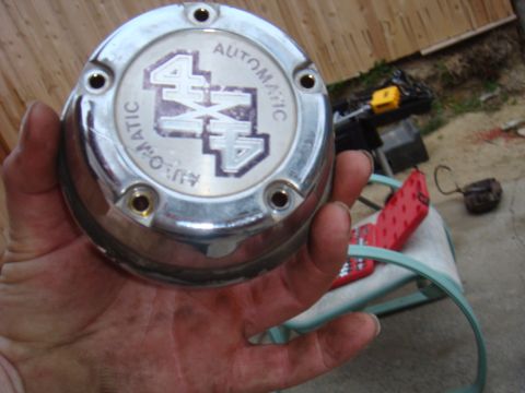 1992 Ford Bronco - Chrome hubcap with 4x4 Automatic branding, held in a hand.