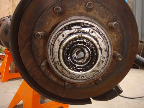 1992 Ford Bronco - Rusted wheel hub and brake rotor assembly on jack stands, likely undergoing maintenance or repair.