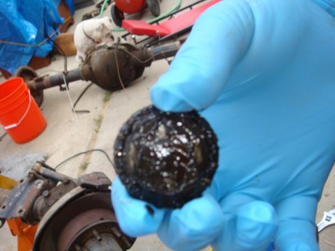 1992 Ford Bronco - A greasy metal part is held up for inspection, with a vehicle axle visible in the background.