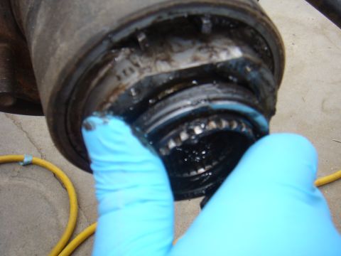 1992 Ford Bronco - A gloved hand is shown manipulating a greasy, toothed component of a vehicle's axle assembly.