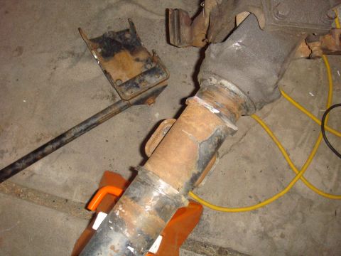 1992 Ford Bronco - A heavily rusted axle assembly, likely from an older vehicle, is supported by orange jack stands in a garage setting.